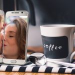 Fernbeziehung mit Smartphones und Kaffeetasse