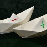 Papierschiffchen mit plus und Minus